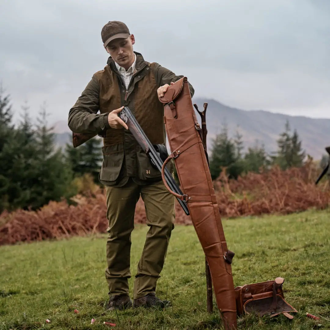 Man in Harkila Rannoch HWS shooting jacket holding a shotgun by a leather case