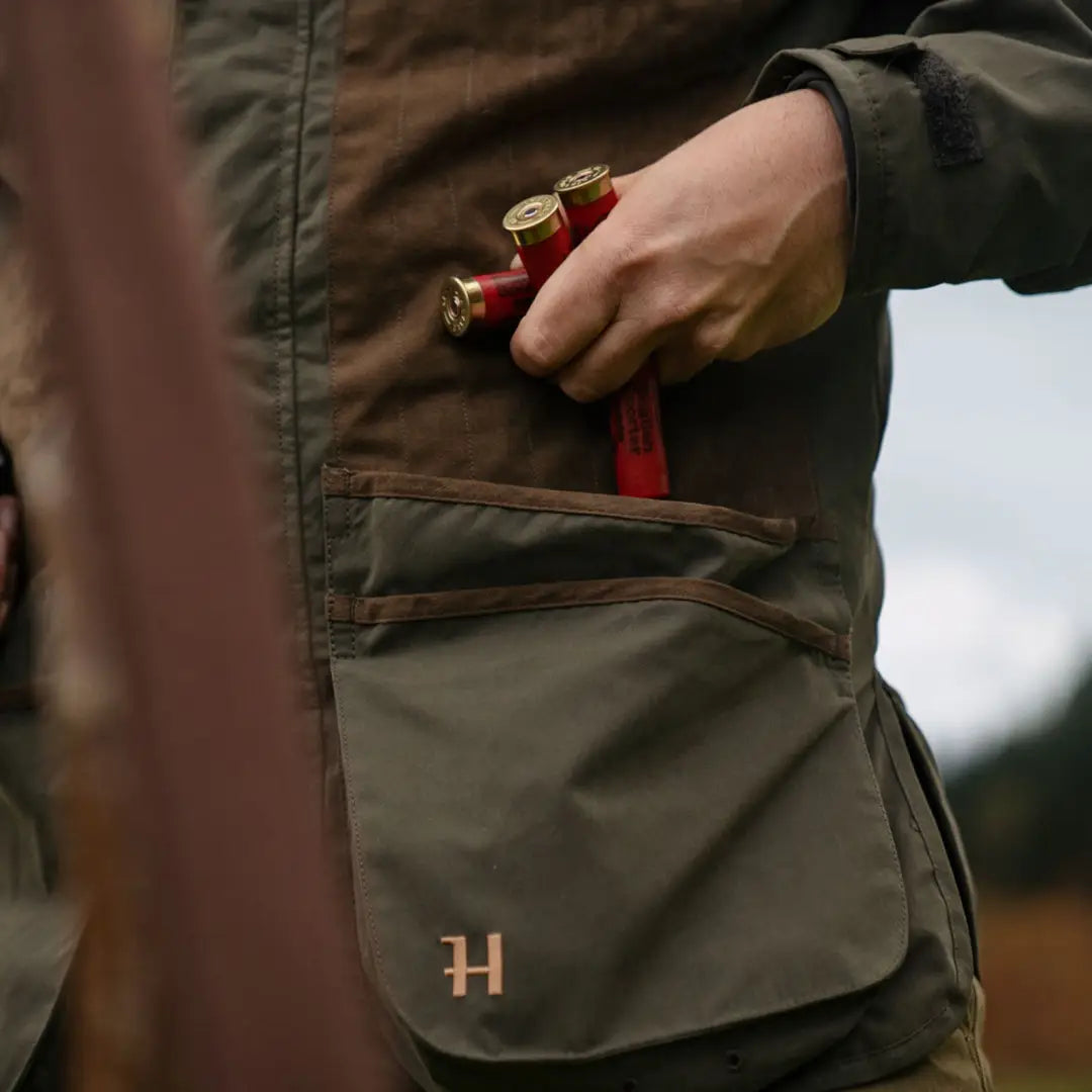 Harkila Rannoch HWS Shooting Jacket with pockets and monogrammed H, holding shotgun shells