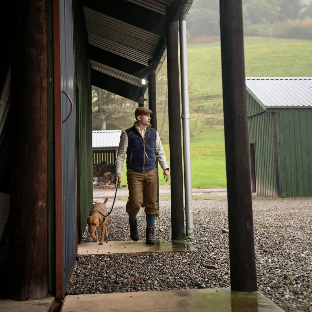 Person in Harkila Sandhem 200 Waistcoat stands in doorway with dog, perfect for country clothing