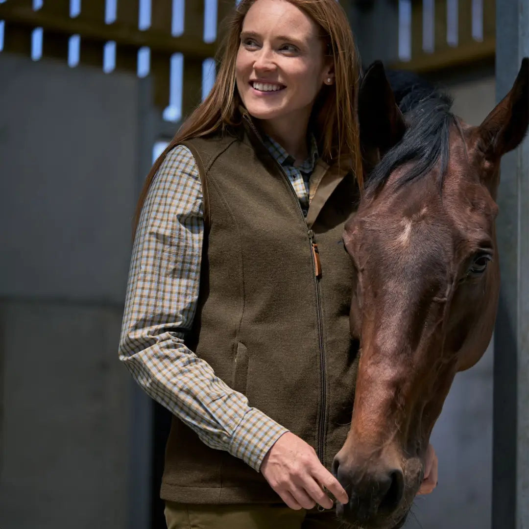 Smiling woman with long red hair next to a brown horse in Harkila Sandhem Pro Waistcoat