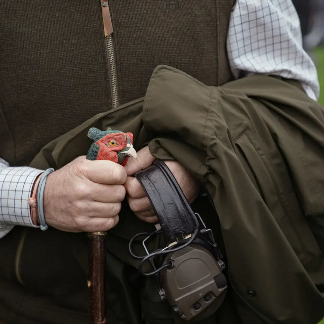 Hunting rifle with ornate trigger guard held by hands in Harkila Sandhem Pro Waistcoat