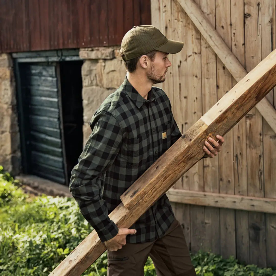 Man carrying a wooden plank, wearing Harkila Scandinavian Long Sleeve Shirt