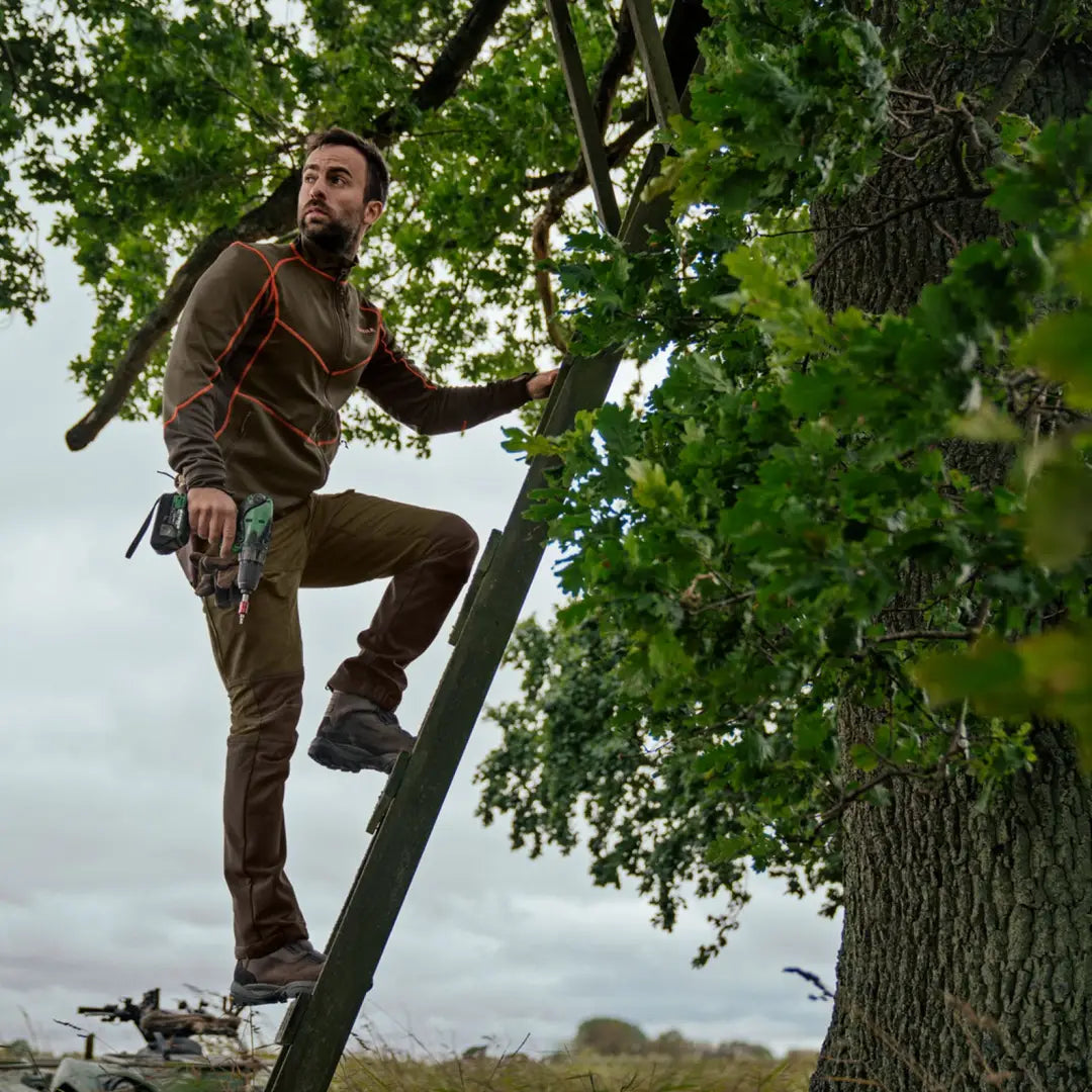 Man climbing a ladder by a tree in Härkila Scandinavian Trousers