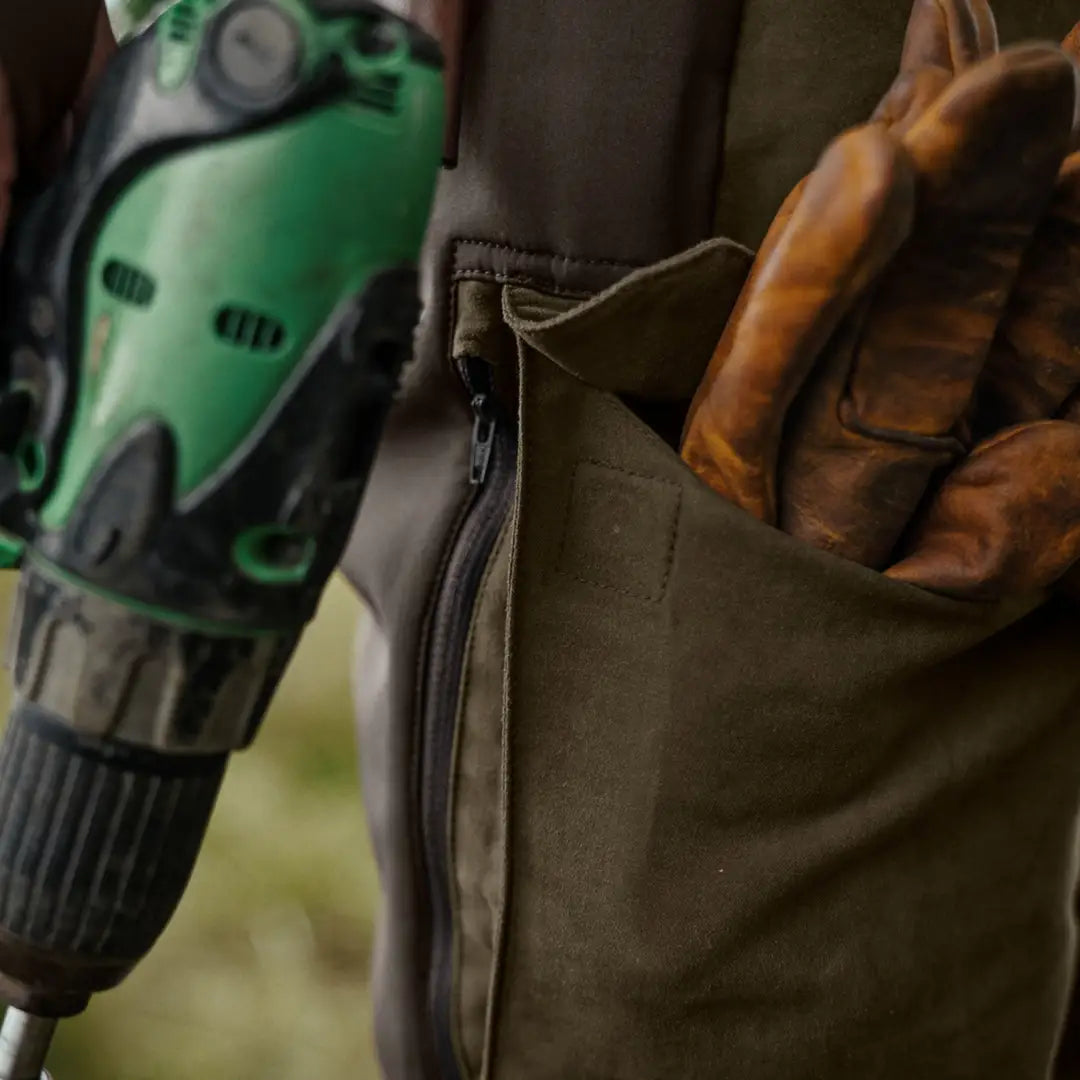 Green electric drill next to Härkila Scandinavian Trousers for stylish work gear