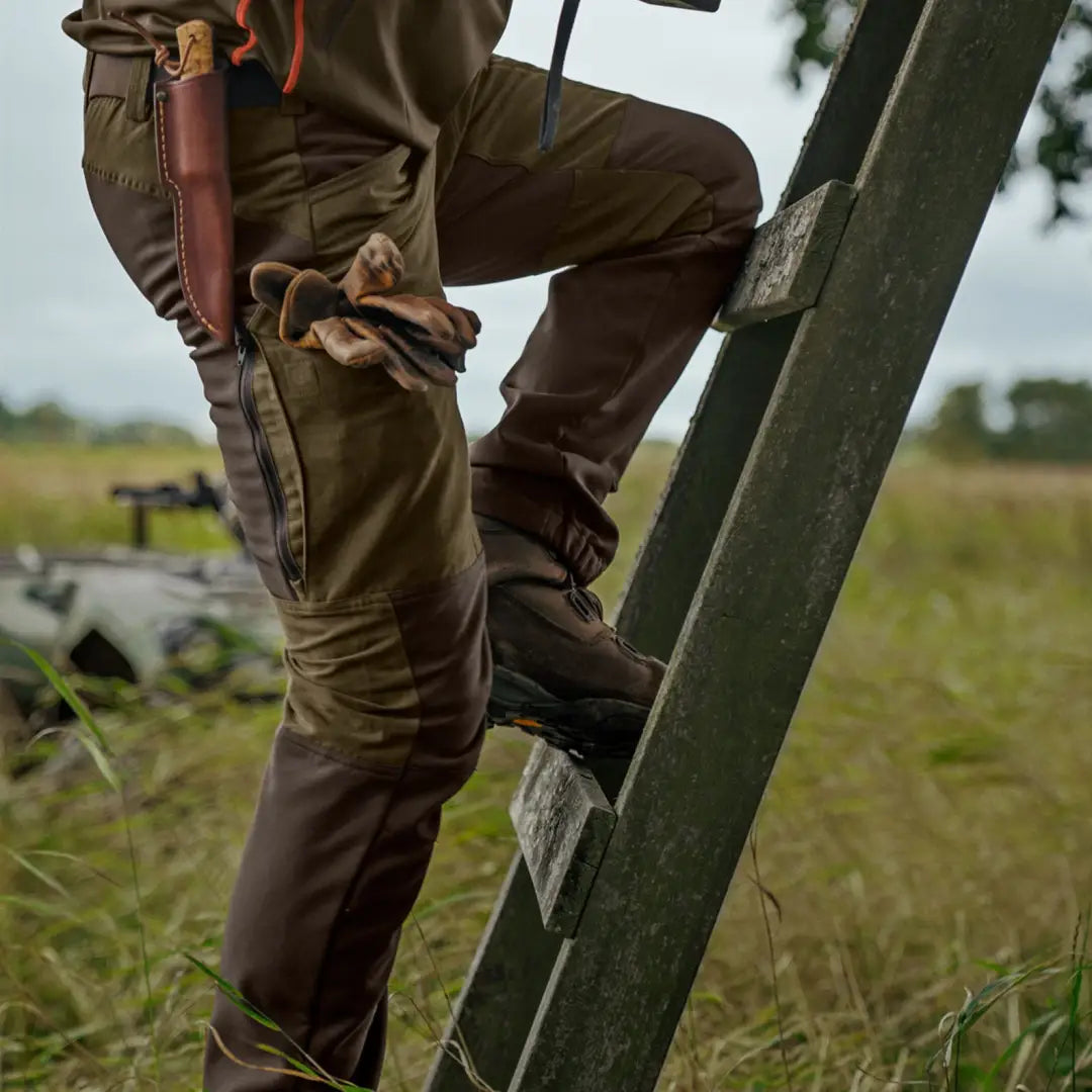 Person climbing a ladder in Härkila Scandinavian Trousers and brown boots