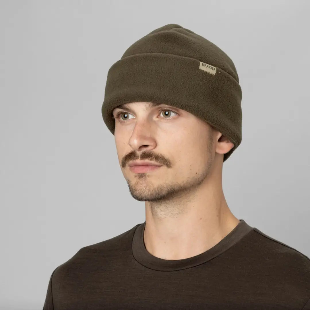 Olive green Harkila Trygve Beanie worn stylishly by a person outdoors