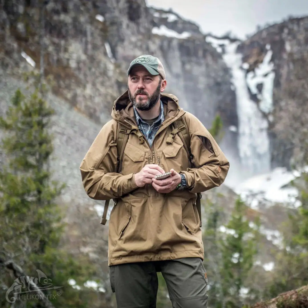 Bearded guy in a tan Pilgrim® Jacket tackling demanding outdoor activities in mountains