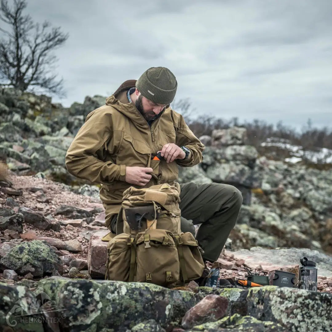 Bearded man in Helikon-Tex Pilgrim jacket prepping gear for demanding outdoor activities