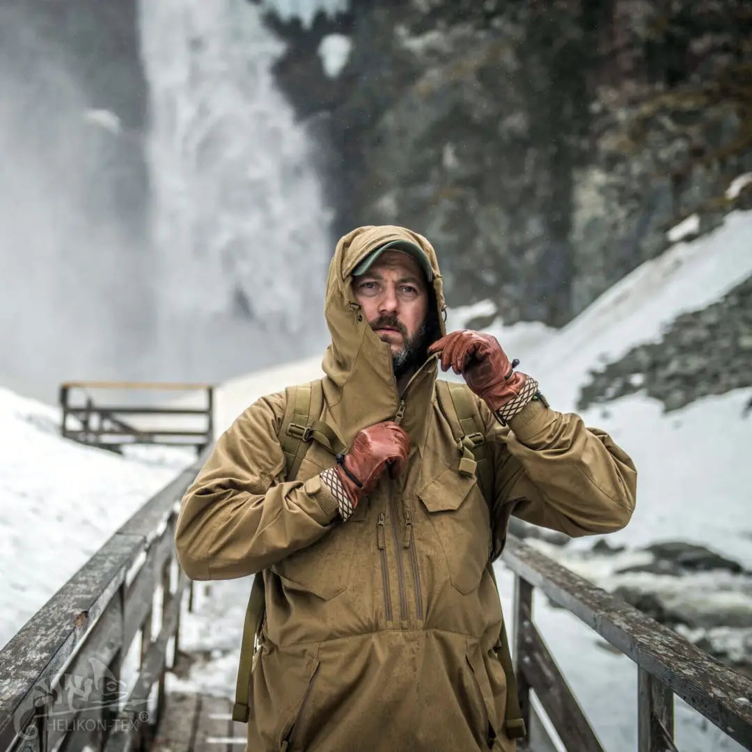 Person in a tan Pilgrim® Jacket on a snowy bridge, perfect for demanding outdoor activities