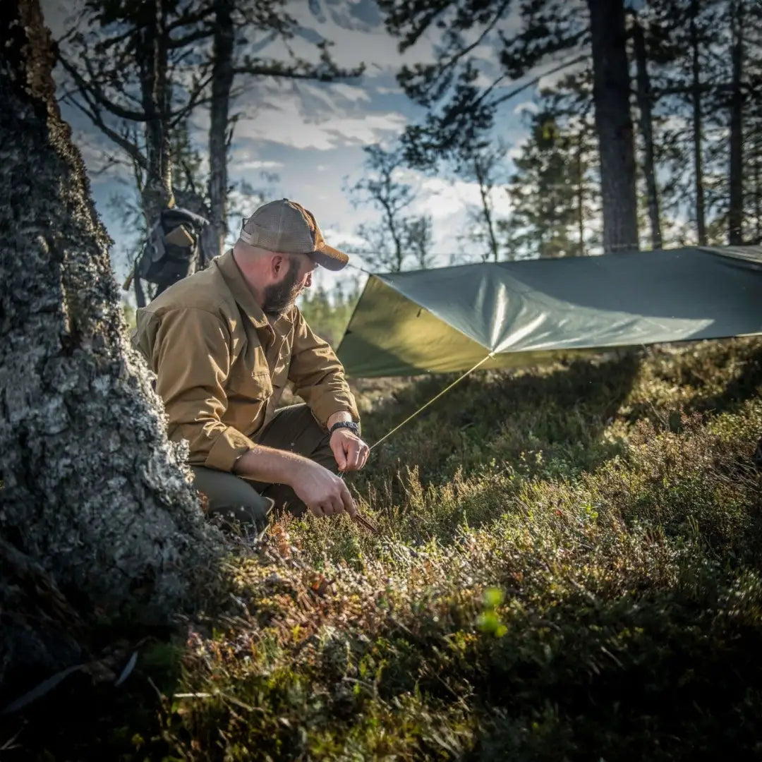 Camper using Helikon-Tex Supertarp Small for shelter in harsh weather conditions