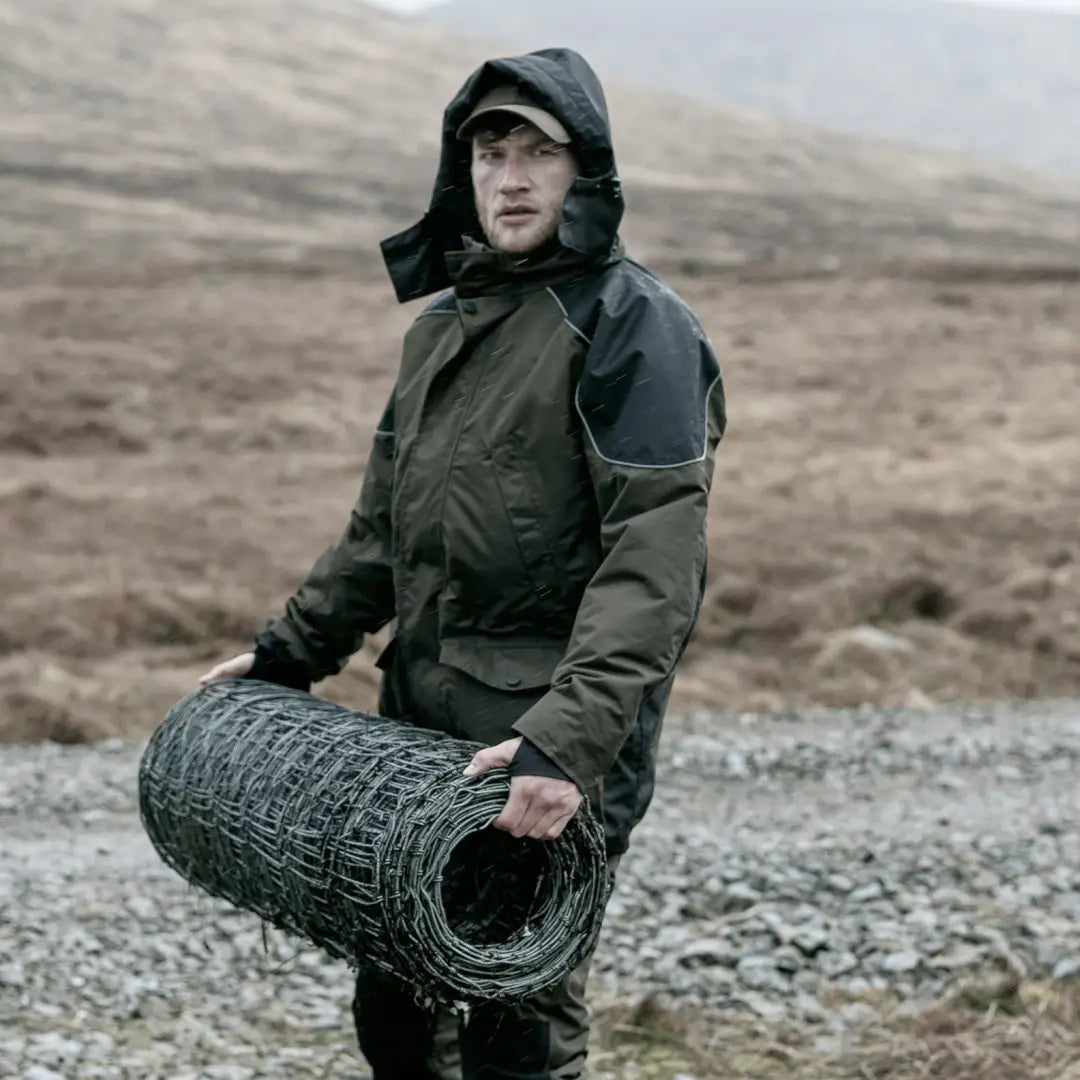 Person in Hoggs Of Fife Field Tech Waterproof Jacket carrying rolled-up wire fence for day long country working