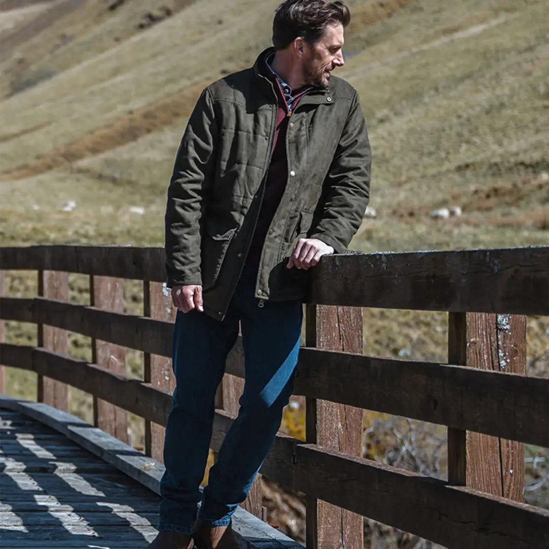 Man in a dark jacket leans on a fence, perfect for country clothing and outdoors