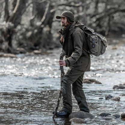 Hiker crossing a rocky stream in a Fife Kincraig waterproof field jacket