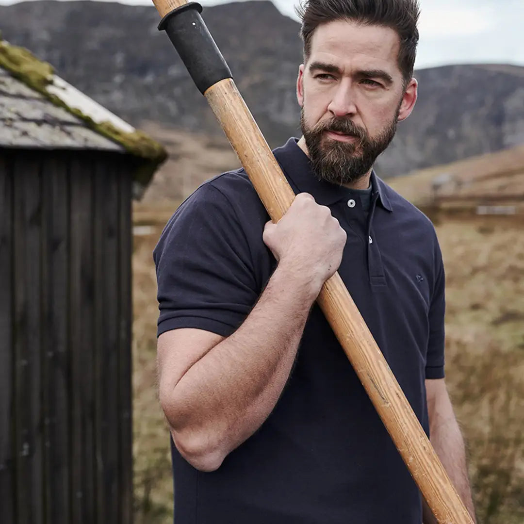 Bearded guy showcasing the rugged vibe of the Fife Largs Polo Shirt with an axe handle