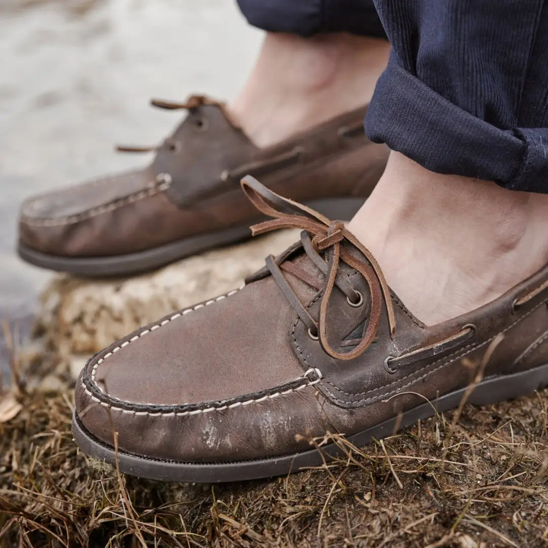 Worn brown leather Fife Mull Deck Shoes resting on grass, perfect for casual outings