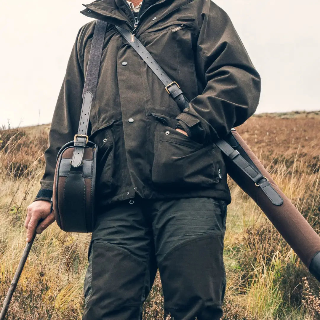 Hunter in dark gear with a rifle showcasing Jack Pyke Ashcombe Jacket style