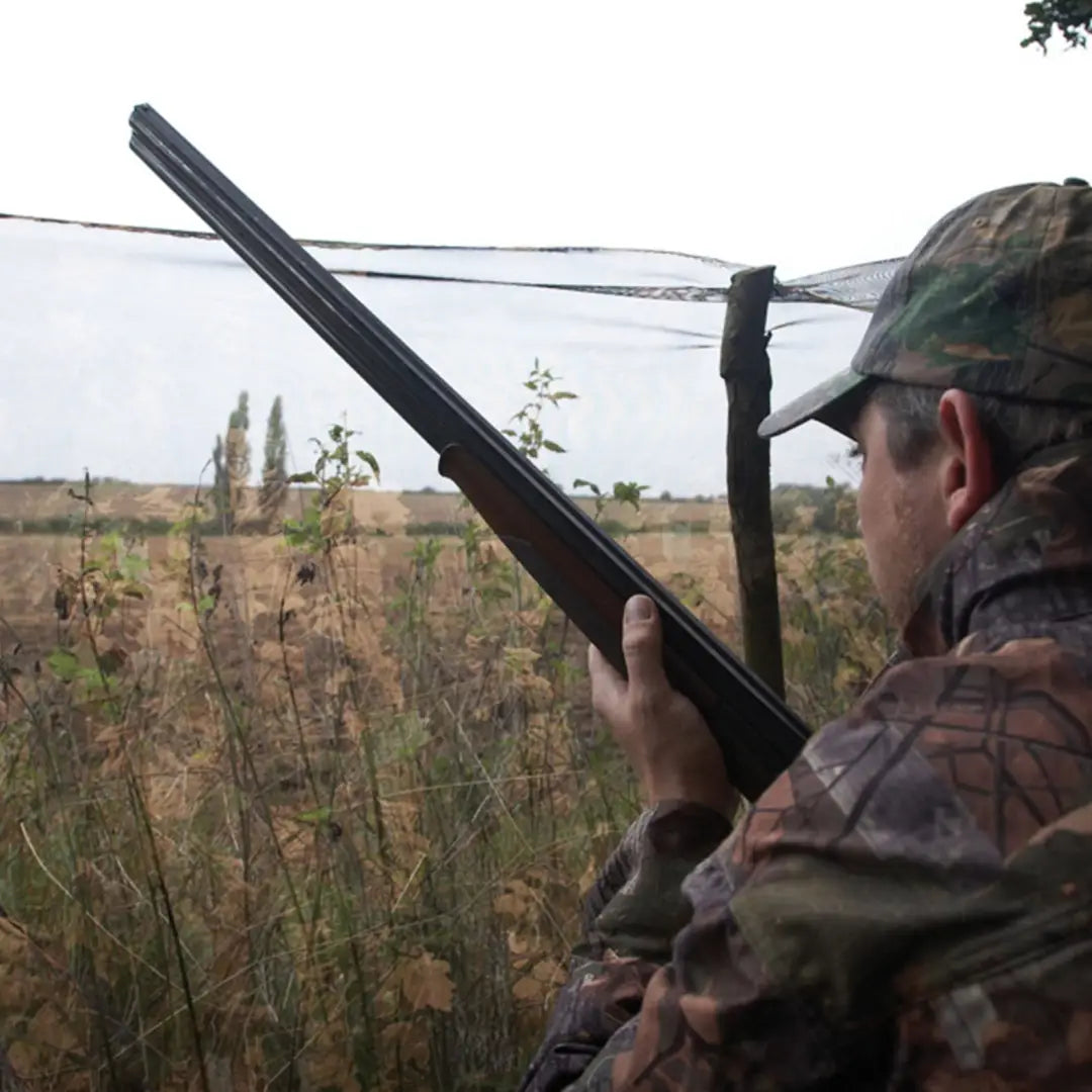 Hunter in camouflage with a shotgun, featuring Jack Pyke Clearview Hide Net for hunting