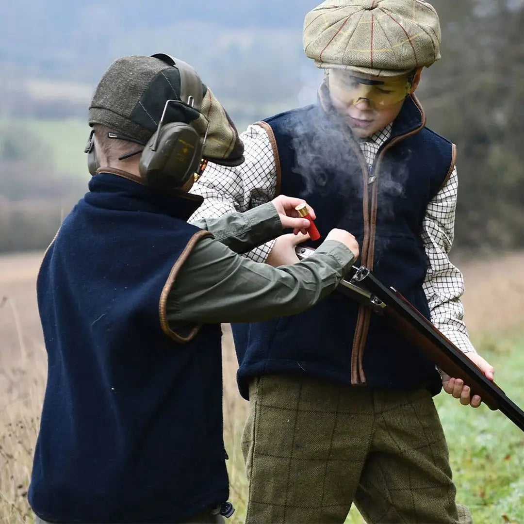 Two hunters in traditional gear inspecting a shotgun, showcasing the Countryman Fleece Gilet