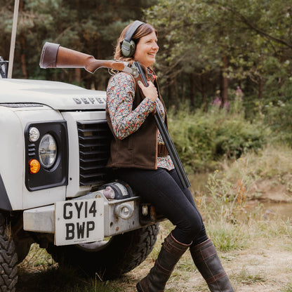 Woman with shotgun leaning on vehicle wearing Jack Pyke Ladies Countryman Fleece Gilet