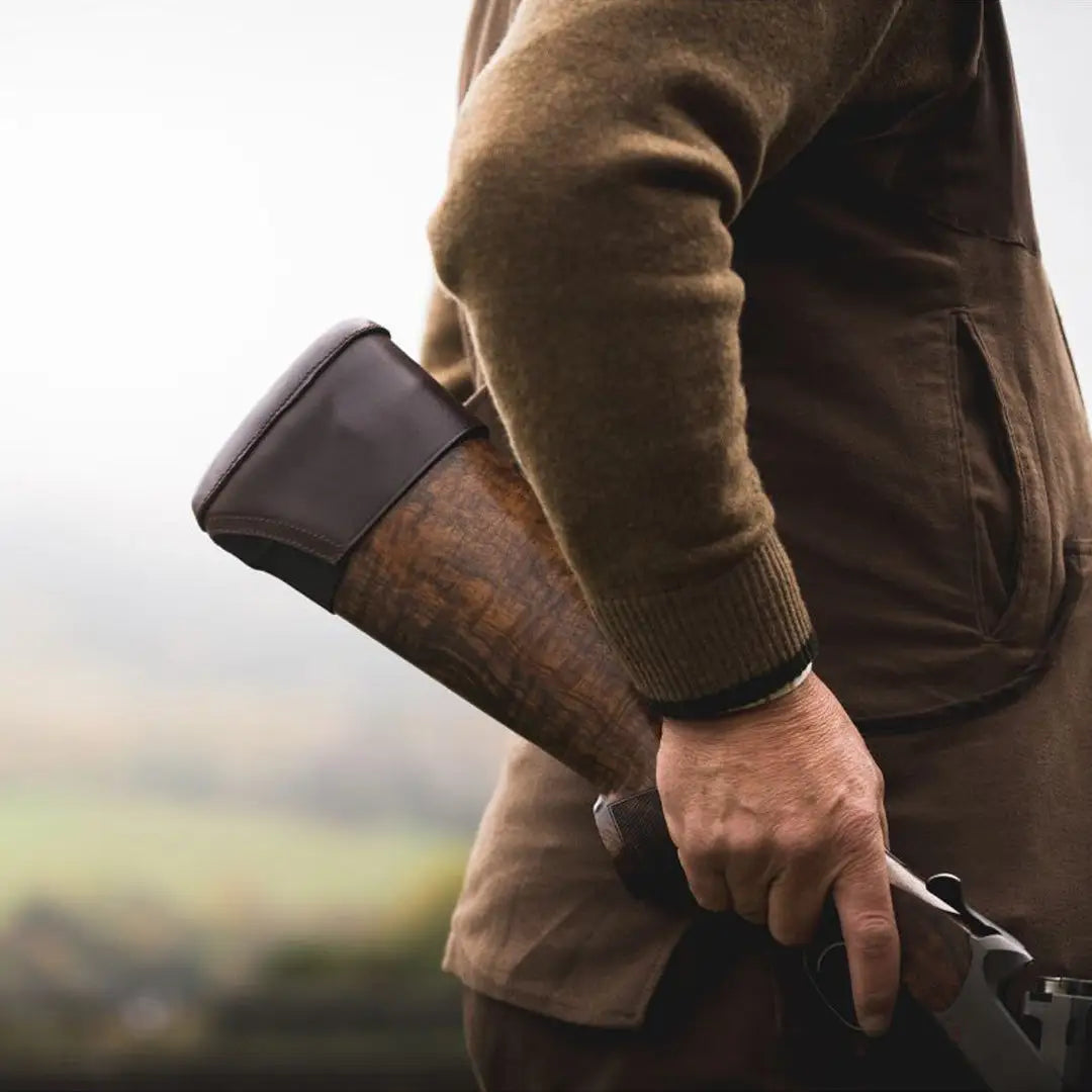 Person in outdoor gear holding a hunting rifle with Jack Pyke Leather Stock Pad