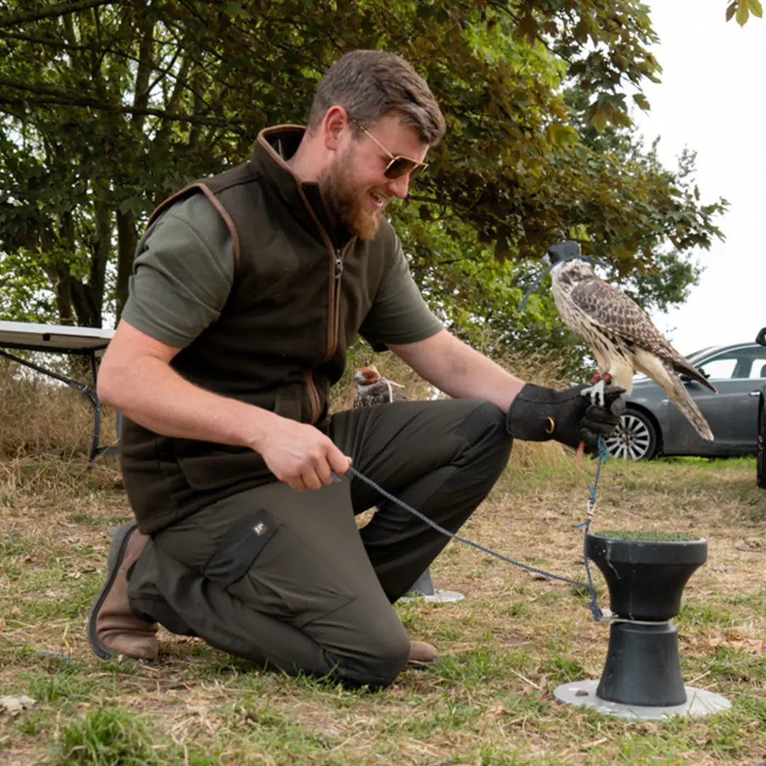 Bearded man in Jack Pyke Softshell Trousers holding a falcon in outdoor setting