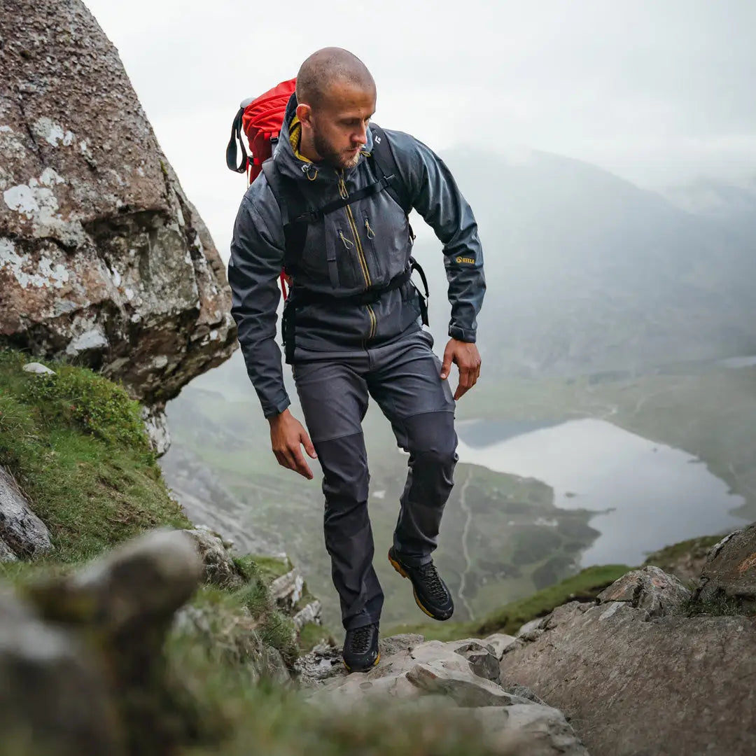 Hiker in a Keela Hydron Softshell Jacket tackling rocky terrain on a misty mountain