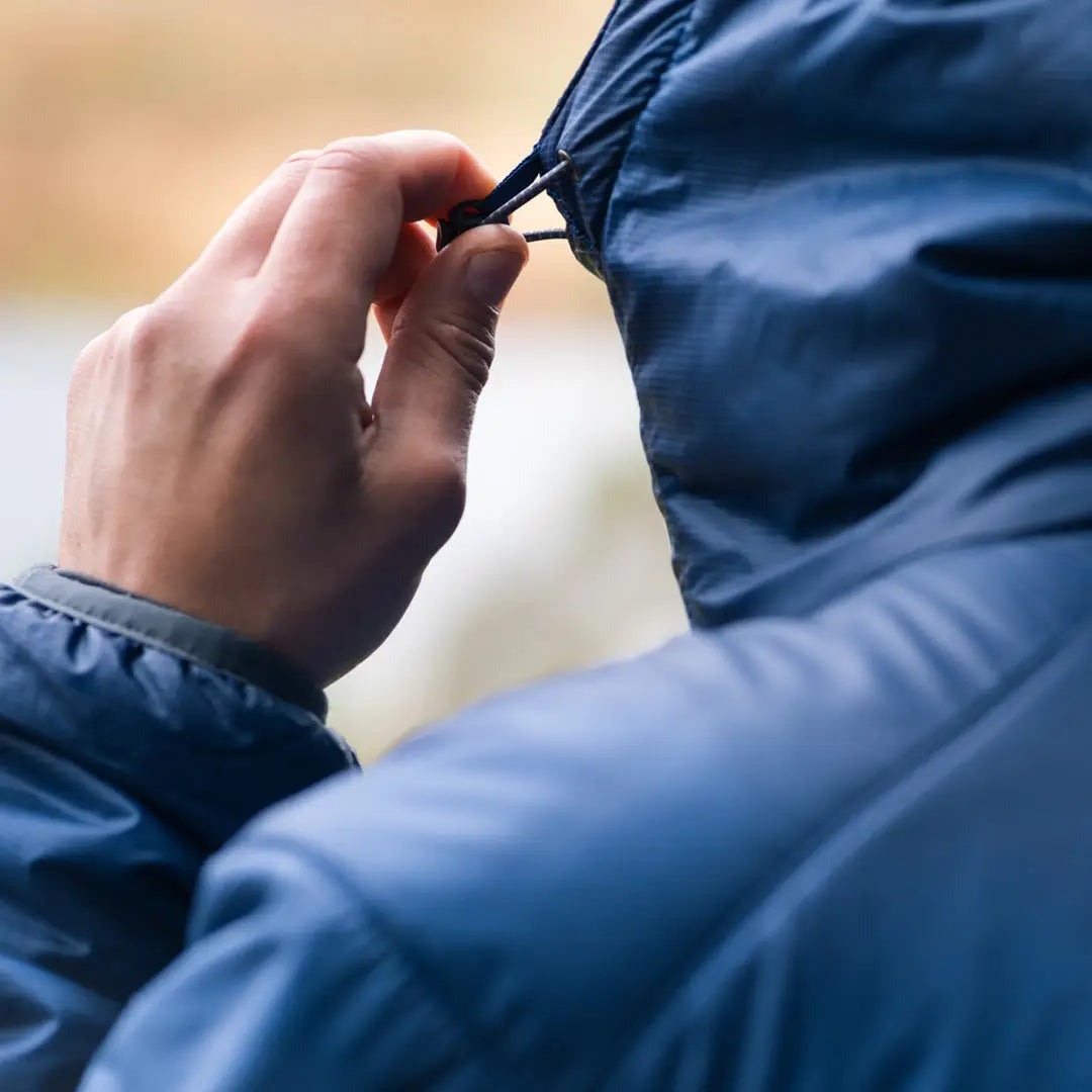 Hand zipping up the collar of a Keela Talus Primaloft Jacket in blue