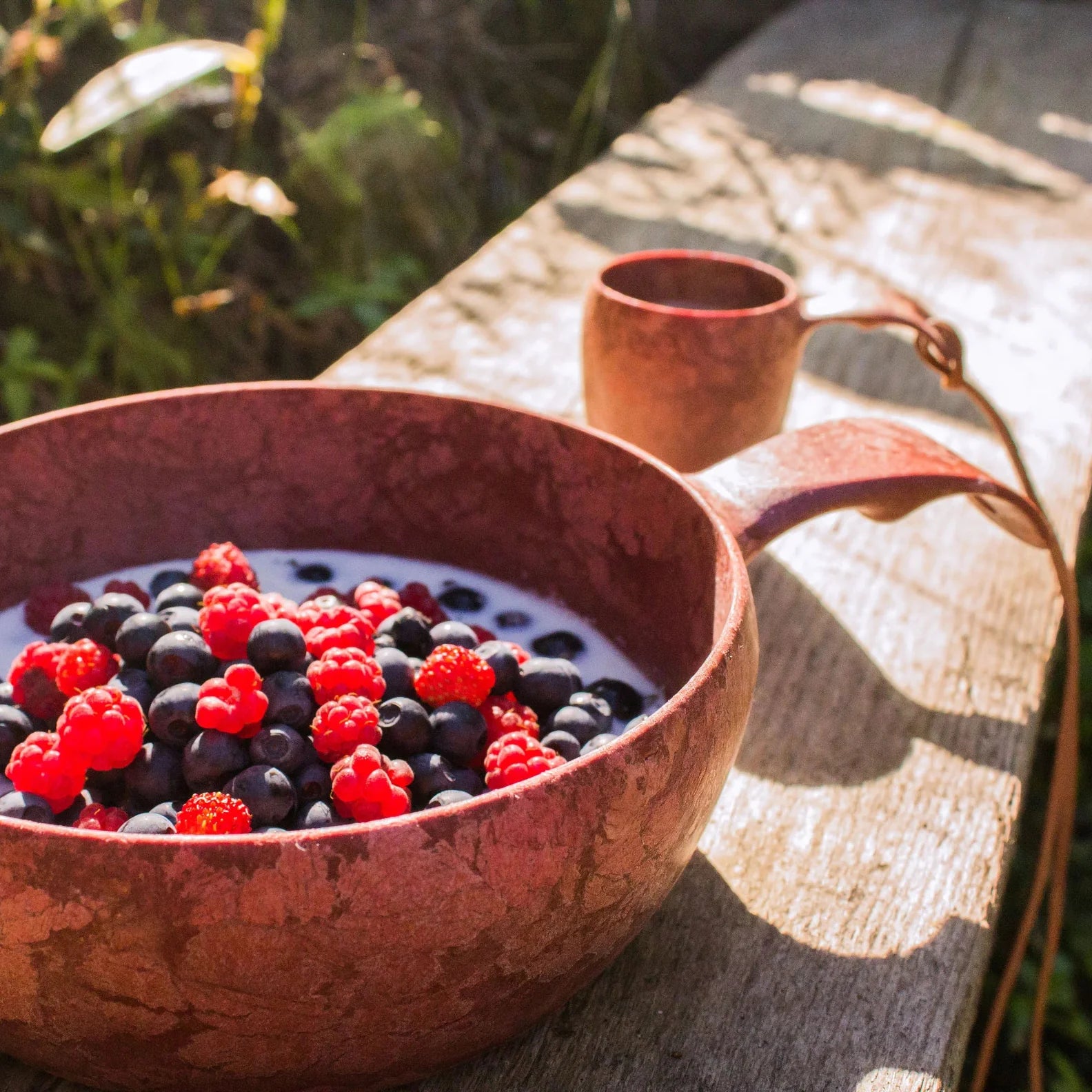 Wooden Kupilka Bowl with fresh berries and milk, perfect for country clothing adventures