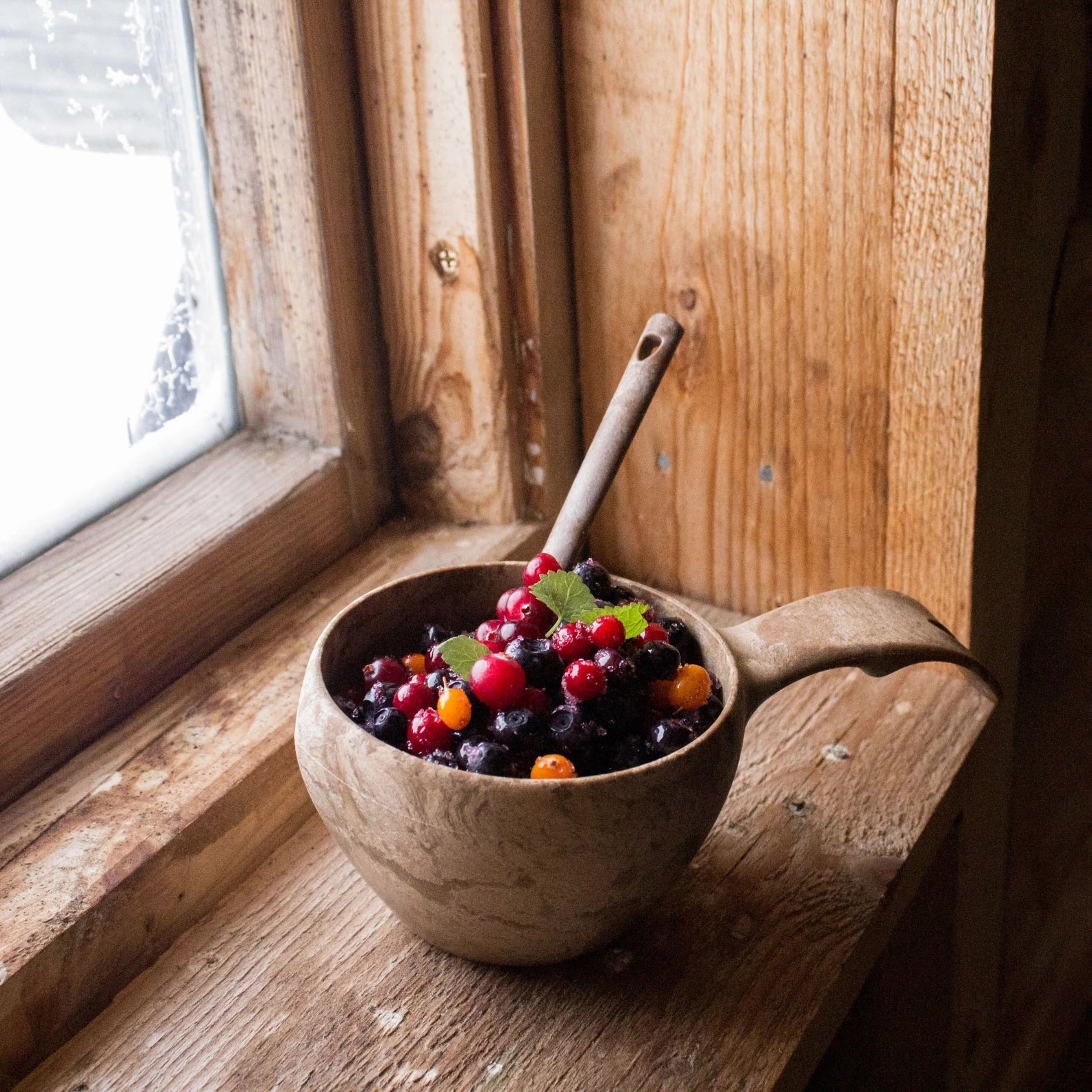 Wooden bowl of mixed berries in a Kupilka Classic Cup for outdoor adventures