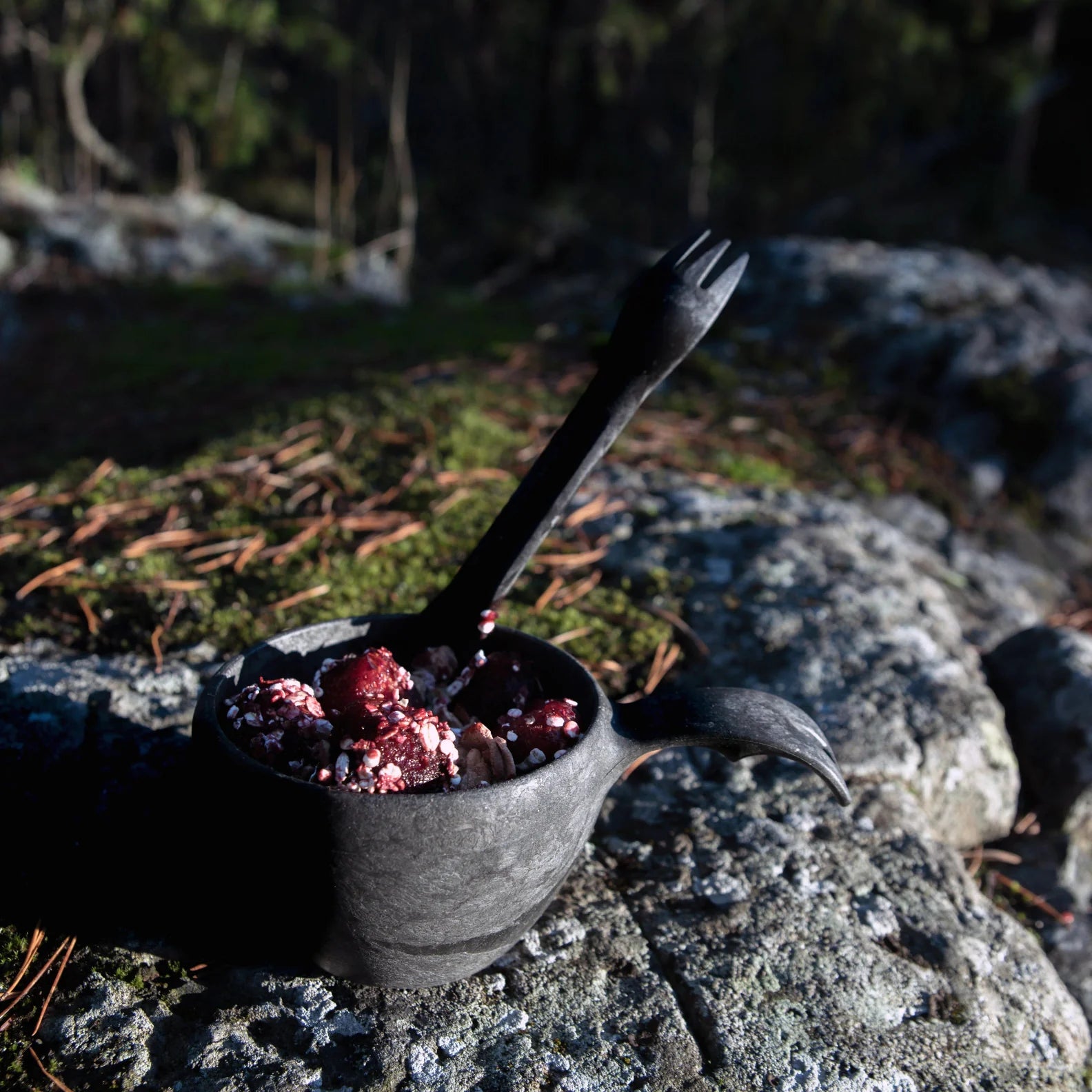 Dark wooden cup with berries and spork from Kupilka, perfect for outdoors and hunting