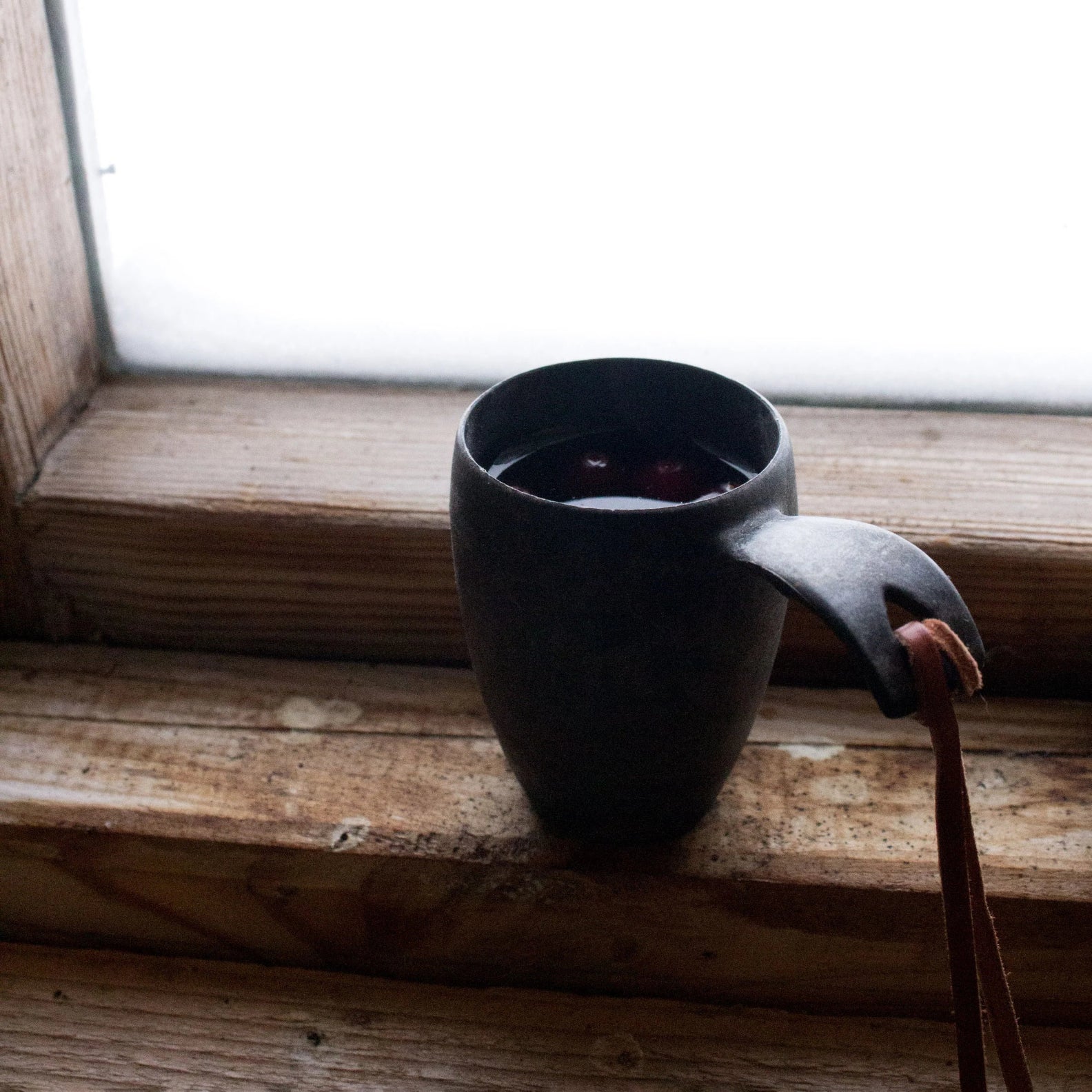 Dark ceramic shot cup with leather strap, perfect for country clothing and hunting trips