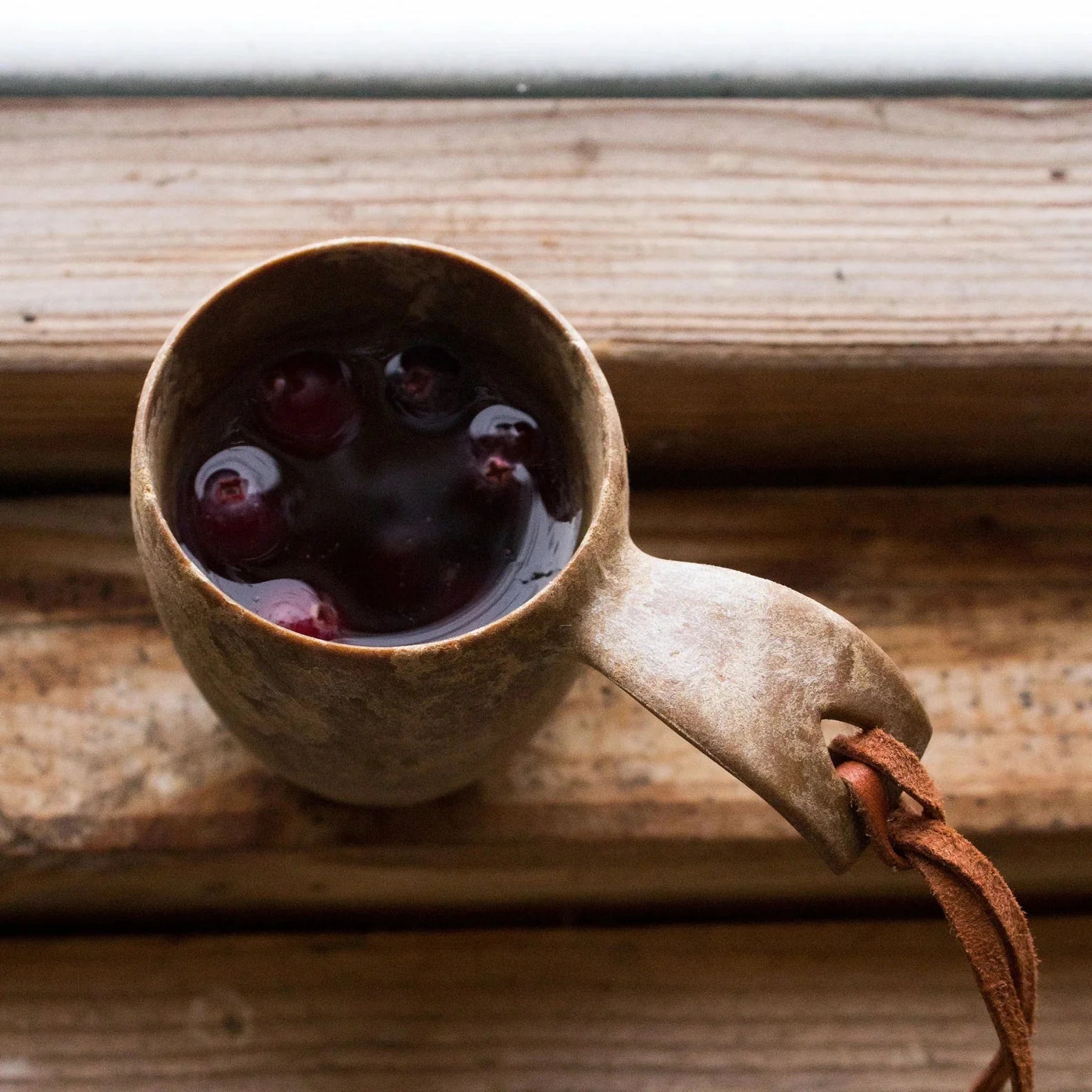 Wooden Kupilka Shot Cup with berries and leather strap, perfect for country clothing and hunting