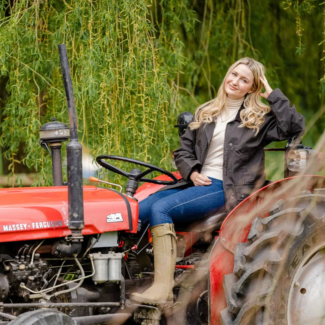 Red vintage tractor with person at controls, perfect for pairing with a stylish ladies padded wax jacket