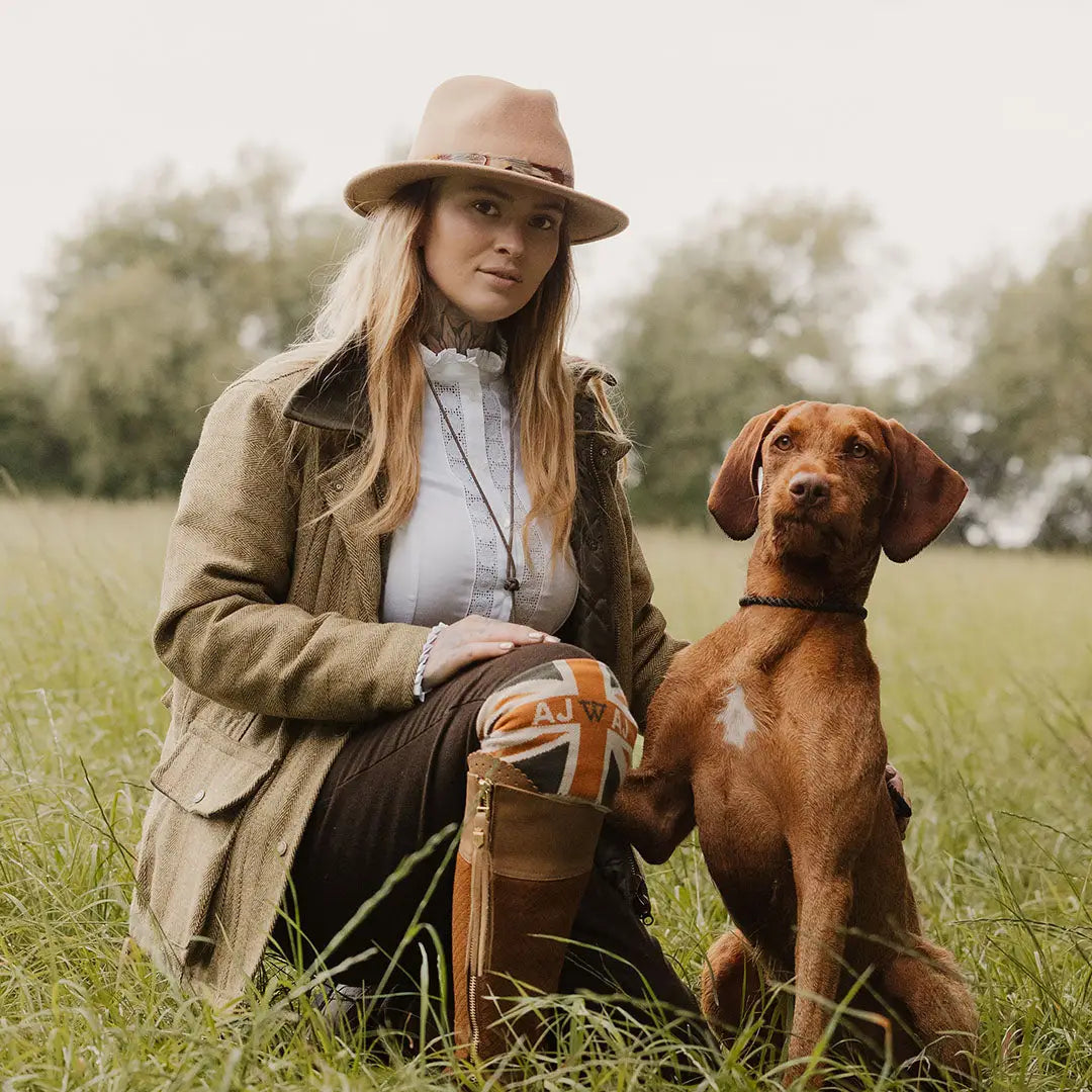 Woman in a fantastic quality ladies tweed jacket sitting with a Vizsla in a grassy field