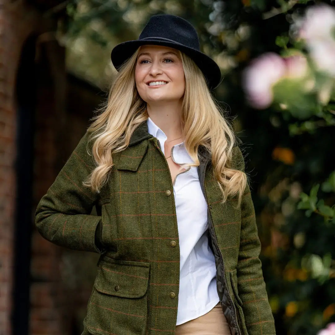 Smiling blonde woman in a green ladies tweed jacket and dark hat, stylish look