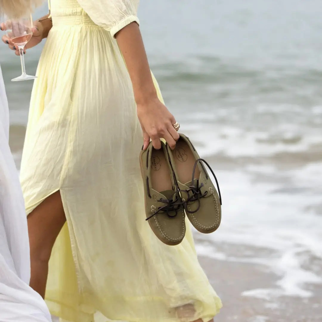 Pale yellow flowing dress with sandals and wine glass next to Galion Nubuck Deck Shoes