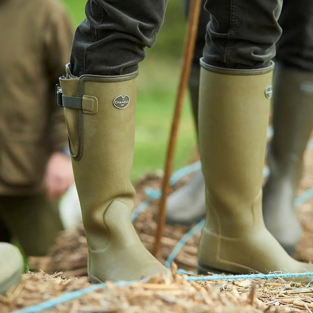 Tall olive green Chameau men’s Vierzon Wellington boots on straw or hay