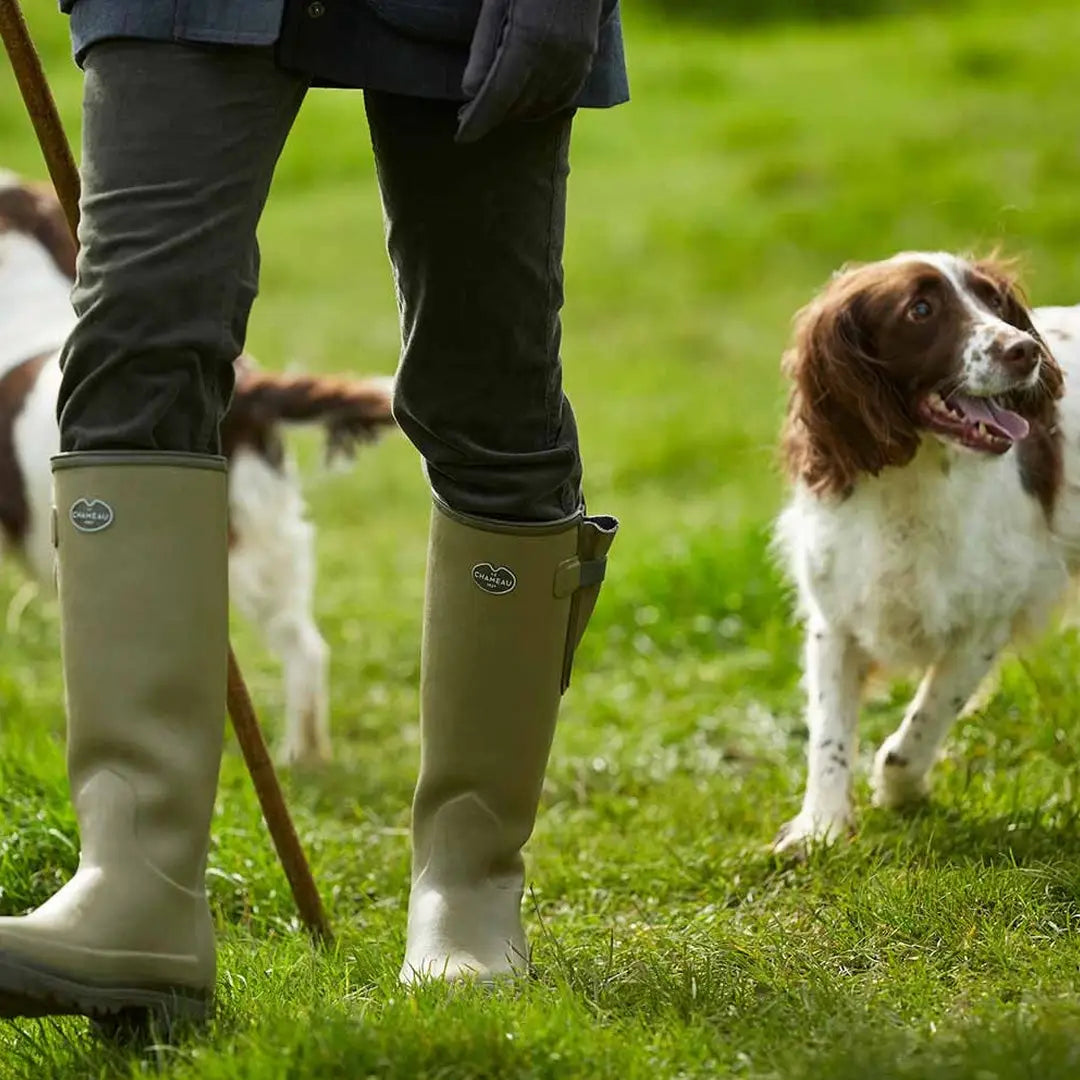 Spaniel dog and a person in green Chameau Vierzonord Wellington Boots on grass