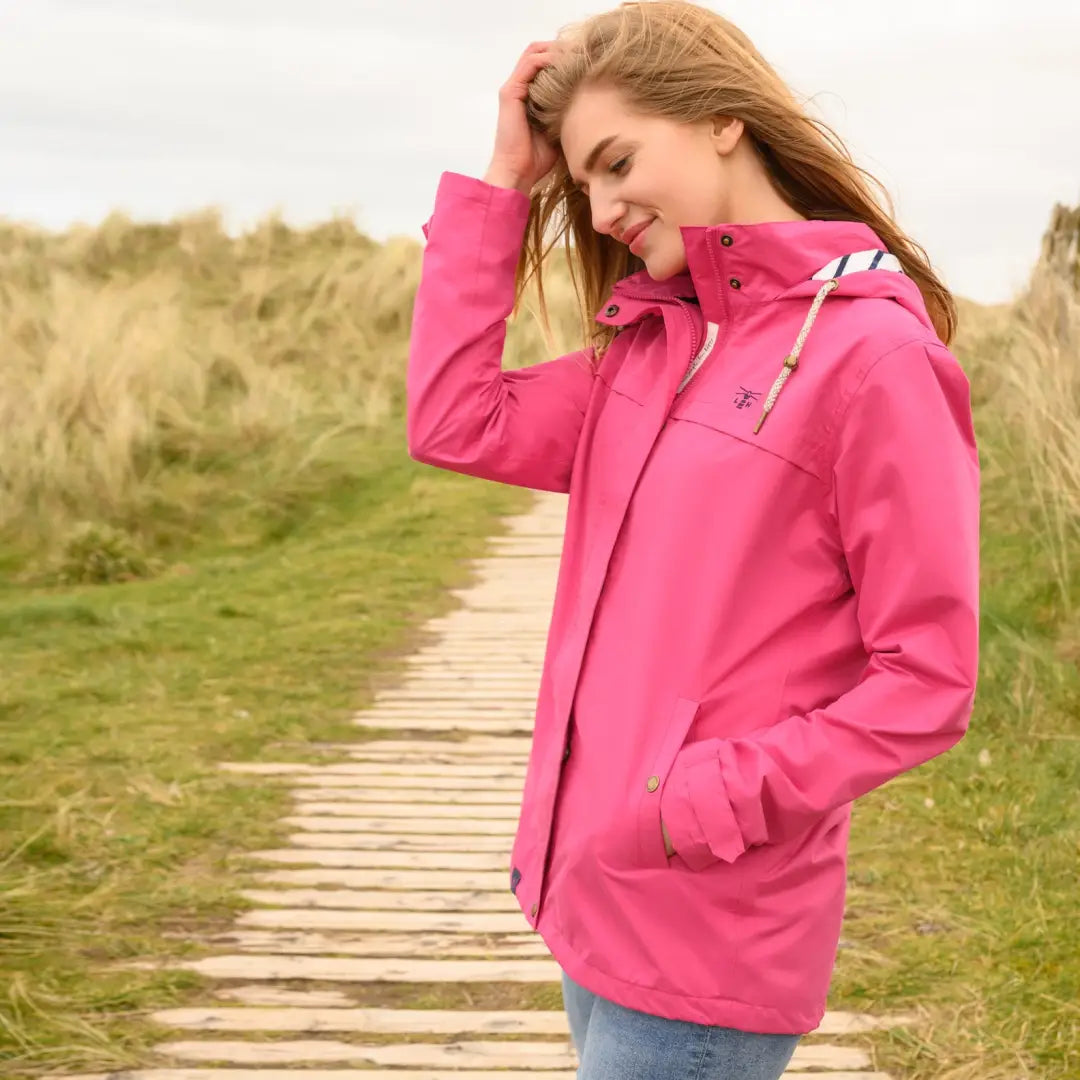 Bright pink Lighthouse Beachcomber Ladies Waterproof Jacket worn outdoors by a woman