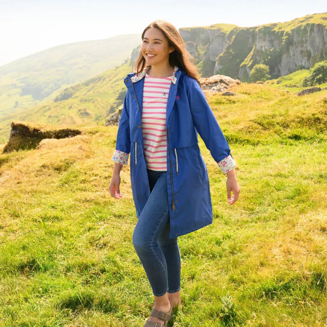 Woman in a blue Lighthouse Ladies Pippa Coat and striped shirt on green grass