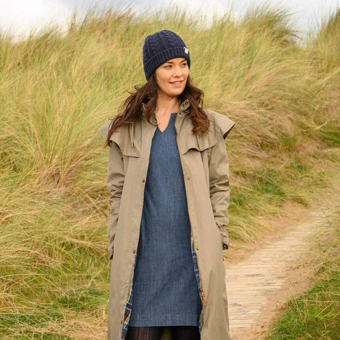 Woman in a beige trench coat and blue knit hat wearing Lighthouse Outback ladies waterproof raincoat