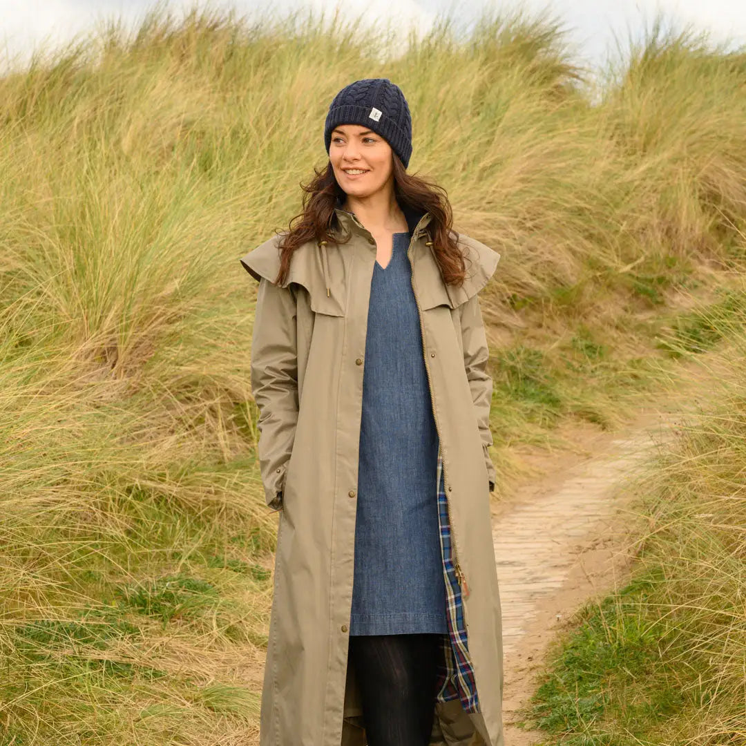 Woman in a long beige coat and navy hat wearing a Lighthouse Outback ladies waterproof raincoat