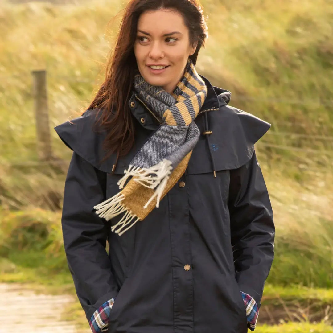 Woman in a navy blue coat and striped scarf wearing a Lighthouse Outrider ladies waterproof raincoat