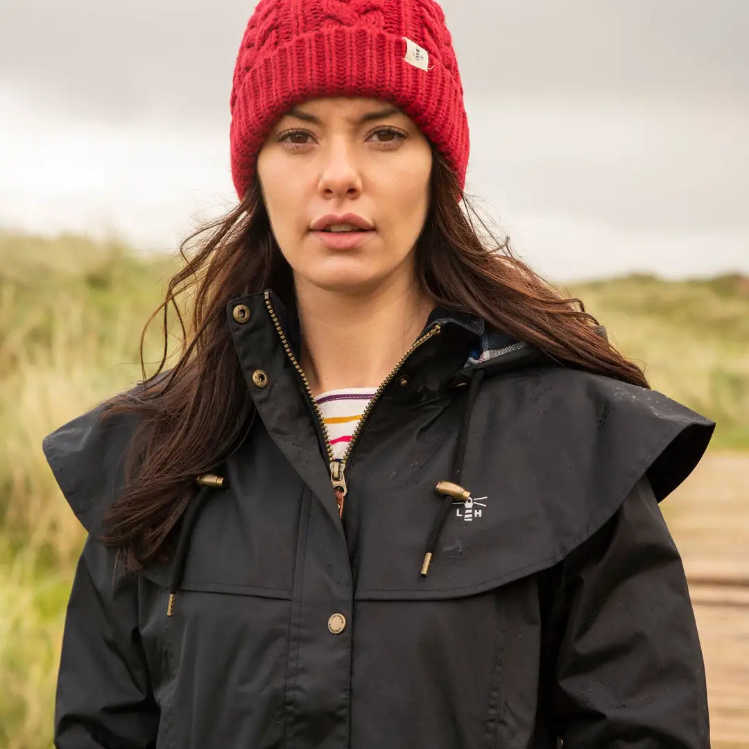 Woman in a red knit hat and black jacket with Lighthouse Outrider ladies waterproof raincoat