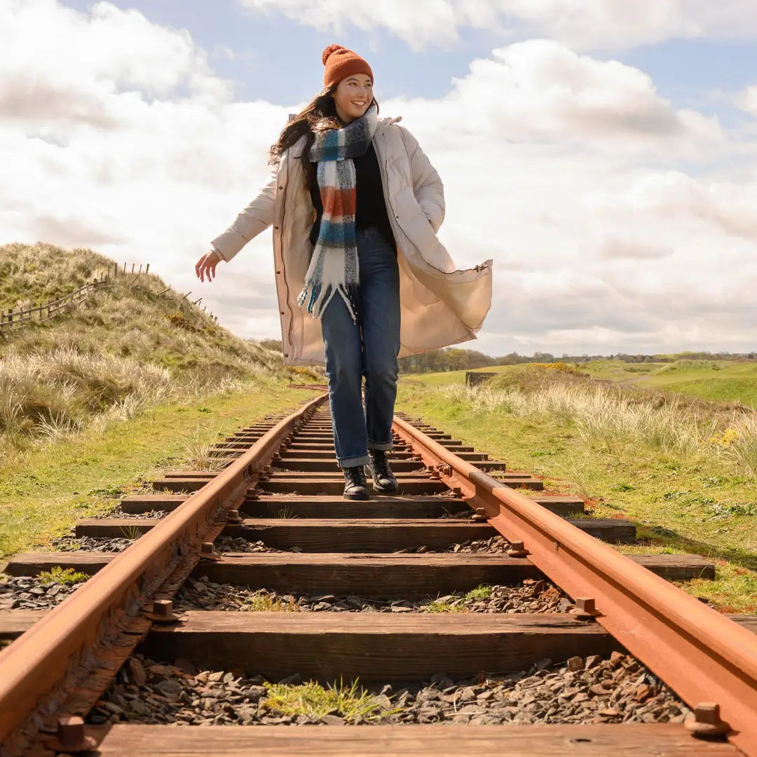 Person in a Lighthouse Savannah Coat walking on railroad tracks in autumn