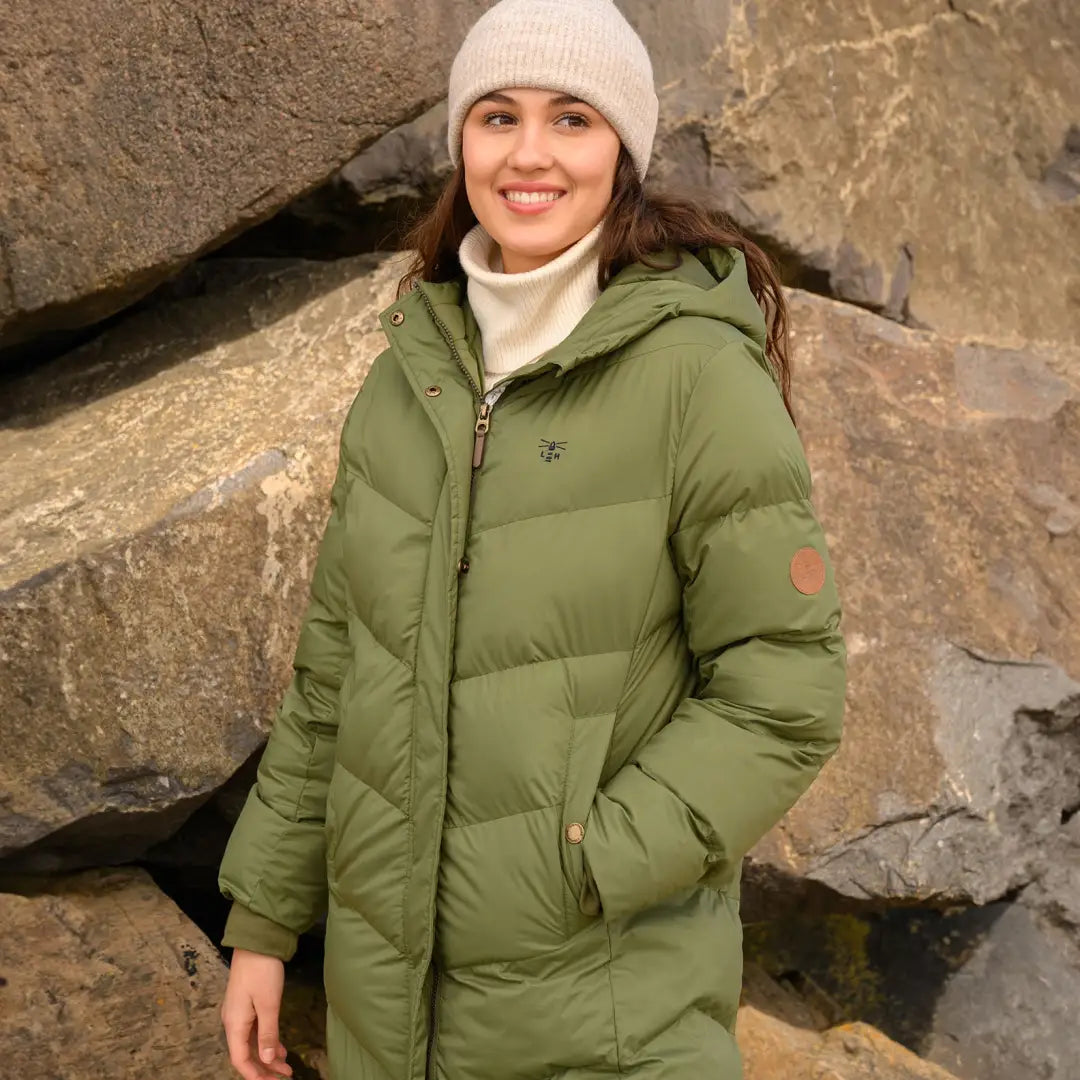 Woman in a green puffer jacket with a white knit hat, featuring a secure zipped internal pocket