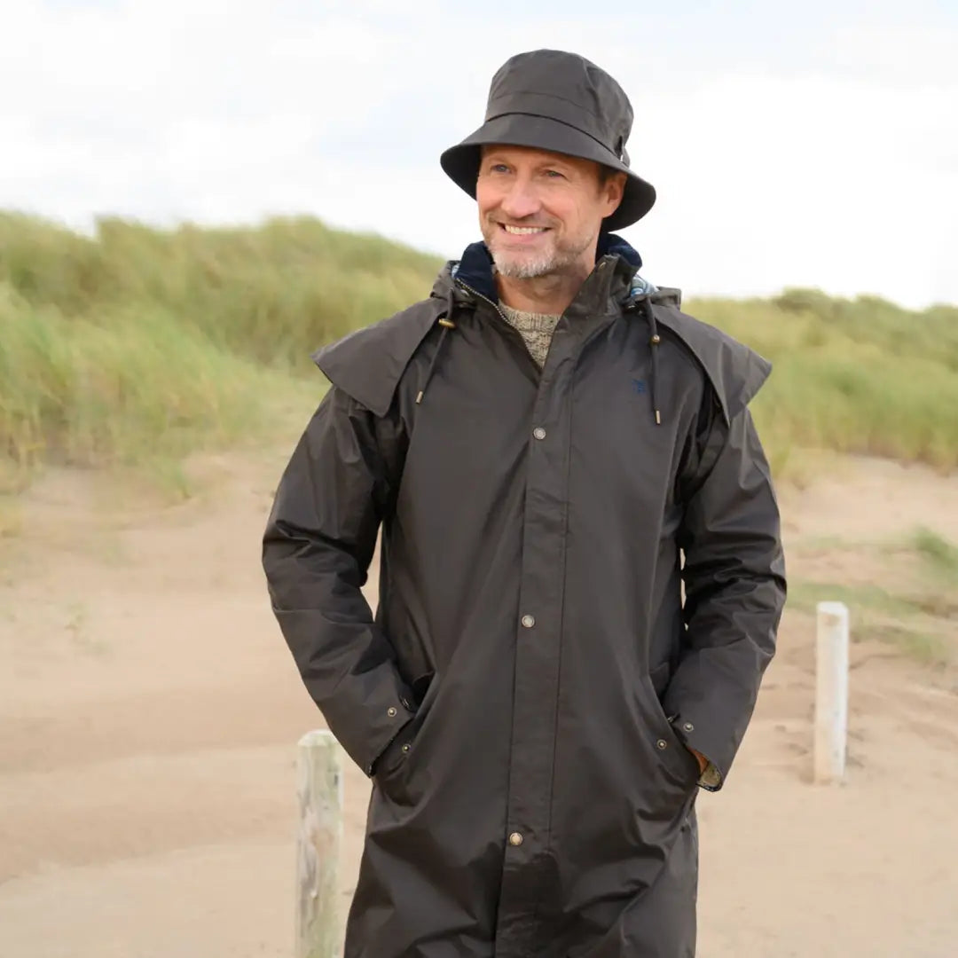 Smiling man in a dark Lighthouse Stockman full length waterproof rain coat outdoors