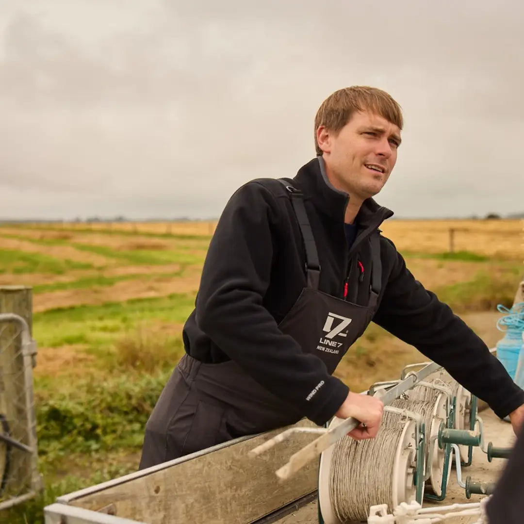 Man in a black Line 7 Wind Pro 1/2 Zip windproof fleece jacket operating a winch outdoors