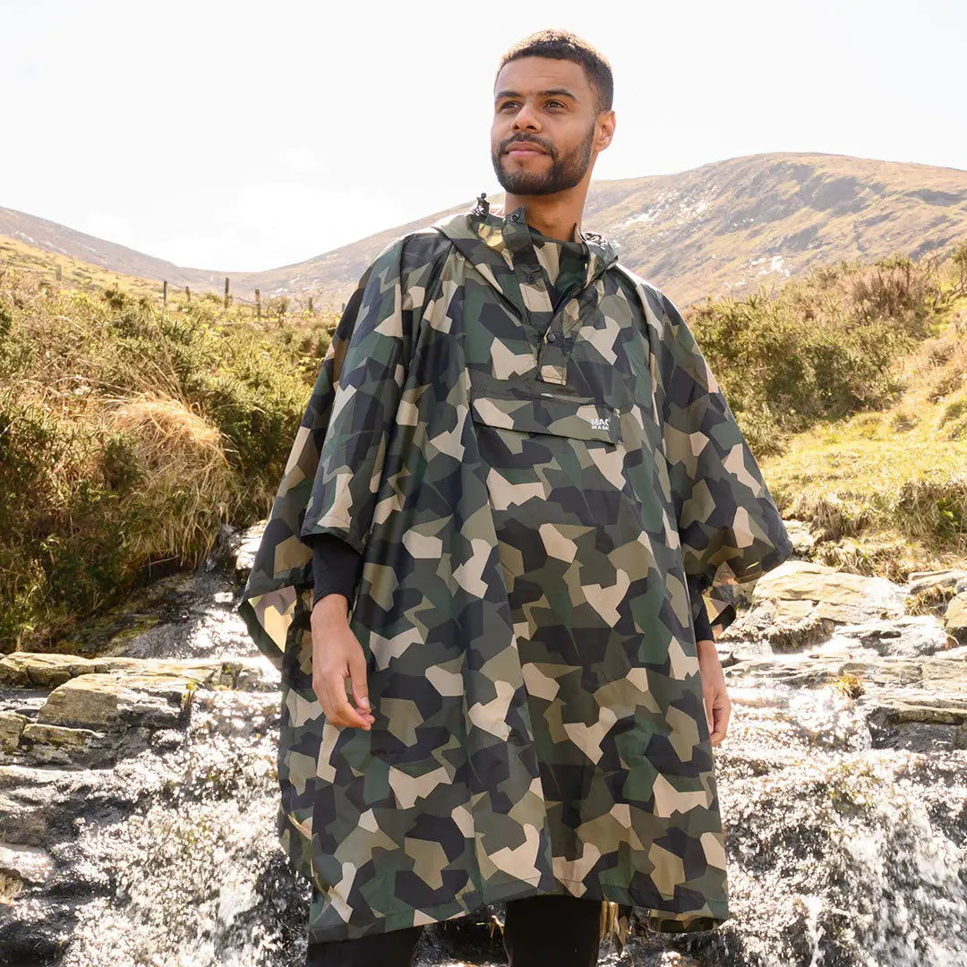 Man in outdoor setting wearing Camouflage Mac In A Sac Origin 2 Poncho