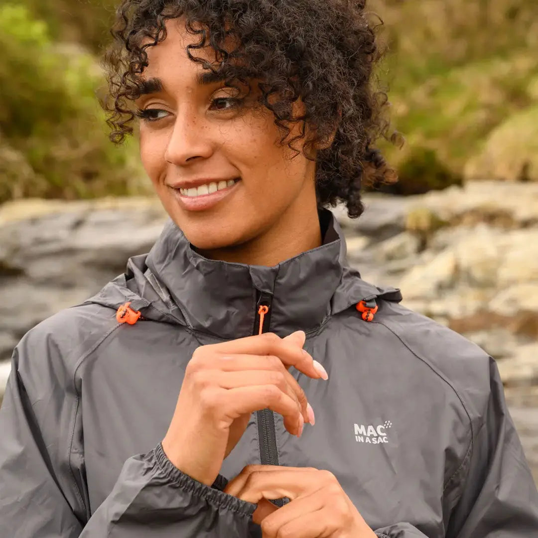 Gray MAC waterproof jacket with fully taped seams worn by a smiling person with curly hair